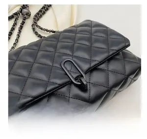 Detailed close-up of quilted black leather texture and oval metal clasp with chain