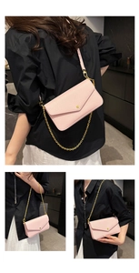 Detail of light pink pebble leather envelope bag with gold chain strap and metal button