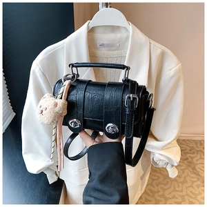 Detail of black croc-embossed messenger bag with silver twist locks and bear charm