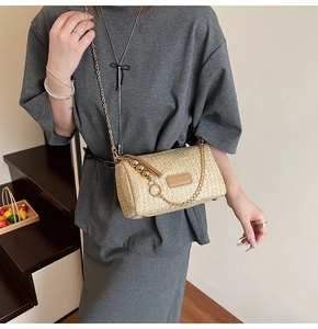 Detail of a beige woven mini crossbody bag featuring a gold chain and metal bead charms