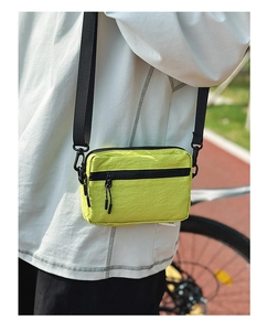 Close-up of fluorescent yellow nylon crossbody bag with dual zippers and adjustable strap
