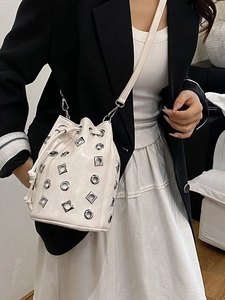 Fashionable cream eyelet bucket bag with metallic studs and drawstring closure