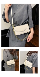 Detail of off-white lychee leather mini crossbody bag with gold chain and snap closure