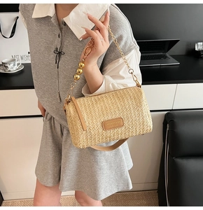 Close-up of woven beige handbag with gold chain strap and brown leather details
