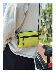 Detail of neon green nylon crossbody bag showing dual zipper pockets and sporty texture
