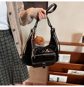 Detail of black faux oil wax leather tote bag with white contrast stitching and bear charm