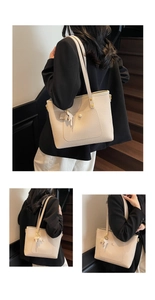 Macro detail of creamy white lychee grain leather tote bag with tassel and round buckle