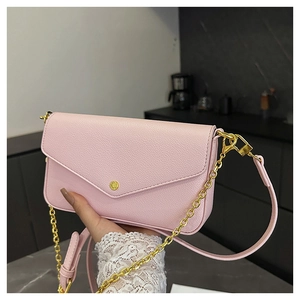 Detail of pink lychee leather envelope bag with gold metal clasp and chain strap