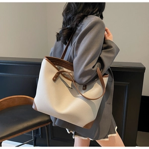 Borsa tote crema minimalista con finiture marroni e tracolla indossata da una modella