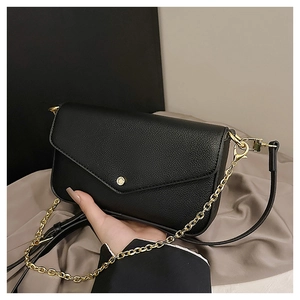 Detail of black pebbled leather envelope bag with gold buckle and metal chain strap
