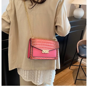 Close-up of pink crocodile pattern envelope bag with golden chain strap and metal lock