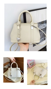 Detail of cream lychee texture leather handbag with silver heart charm and strap