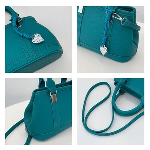 Detail view of lychee grain leather bag with silver heart charm and hardware