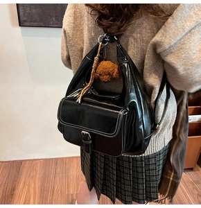 Glossy black oil wax leather backpack with plush dog charm and white stitching detail
