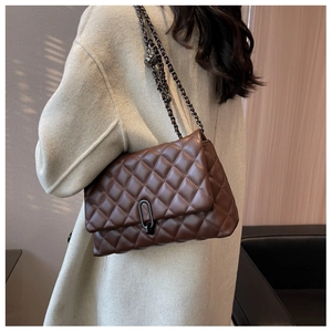 Detail of a brown quilted chain bag with a gold metal ball slider and stylish flip clasp