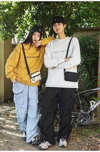 Outdoor street style view of yellow and white sweatshirts with matching nylon crossbody bags