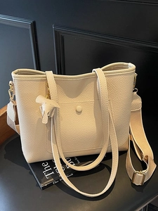 Chic beige lychee grain tote bag with woven strap and charm shown in classic interior