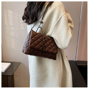 Detail of dark brown quilted chain bag with dark metal clasp shown on a model