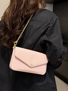 Pink envelope crossbody bag with gold chain strap shown on a model for a stylish look