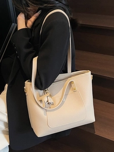 Minimalist beige tote bag with litchi texture and leather horse charm on a model