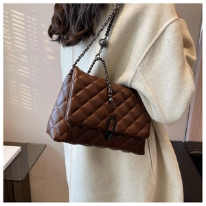Detail of quilted brown chain bag with adjustable metal ball buckle on beige coat