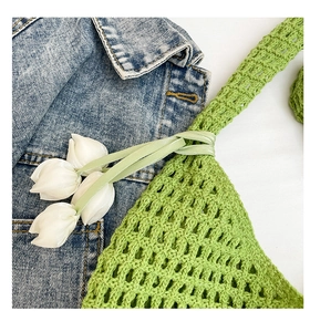 Primer plano de bolso shopper de ganchillo verde con diseño calado y cinta