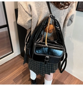 Black glossy shoulder bag with contrast stitching and plush bear charm detail