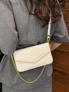 Chic cream white pebble leather envelope bag with gold chain strap on female model