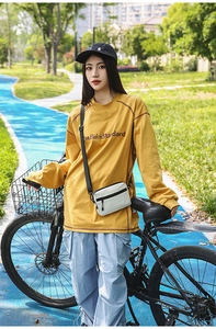 Detail of a ginger yellow long-sleeve cotton T-shirt with white mini crossbody bag