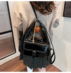 Glossy black oil wax leather shoulder bag with white contrast stitching and bear charm