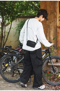Outdoor lifestyle shot of a black nylon crossbody bag worn during a leisure bike ride