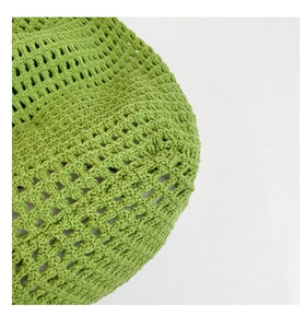 Detalle del patrón de punto de ganchillo verde hierba en un elegante bolso de playa