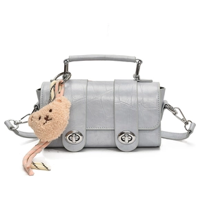 Light blue faux crocodile skin handbag with dual twist locks and plush bear charm accessory