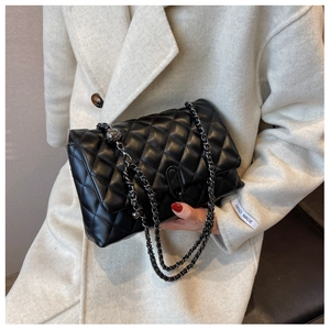 Close-up of black quilted leather chain bag featuring metal lock and elegant stitching