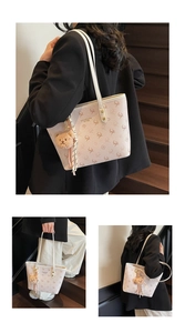 Detailed close-up of a large beige floral tote bag with a plush bear charm and long straps
