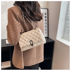 Detail of quilted texture and metal chain strap on an off-white shoulder bag for women