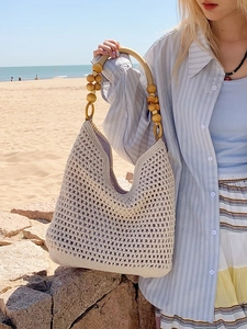 Hollow straw tote bag with wooden bead straps for beach vacations and summer travel