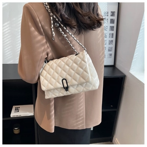 Detailed close-up of white quilted chain bag on shoulder showing texture and metal clasp