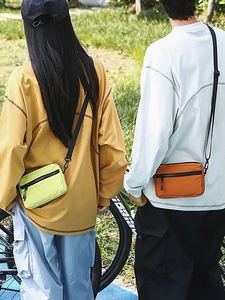 Mini nylon crossbody bag in neon green and burnt orange shown in outdoor leisure setting