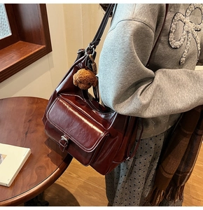 Close-up of retro burgundy faux leather shoulder bag with plush bear charm detail