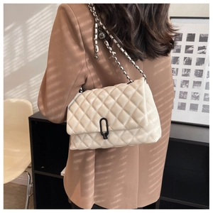 Detail of cream quilted crossbody bag with black U-shaped lock and leather chain strap