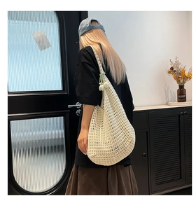 Detalle de bolso de hombro de ganchillo blanco con dije de flor verde menta y malla hueca