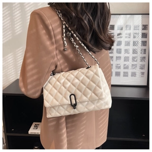 Chic beige quilted crossbody bag with black chain strap on a model in a brown blazer