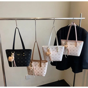 Detail of four patterned tote bags with deer prints and plush bear charms on hangers