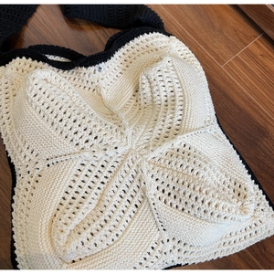 Detail des handgefertigten Baumwoll-Häkelmusters mit schwarzen Kontrastkanten am beige Beutel