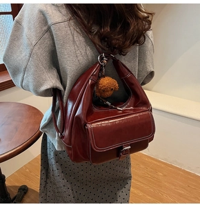 Macro detail of wine red faux leather backpack with white stitching and bear charm