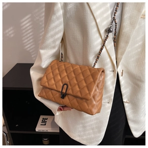 Detail of camel quilted crossbody bag with metal chain strap and U-shaped buckle closure