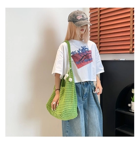Detail of green crochet shoulder bag featuring white 3D floral accents and hollow knit