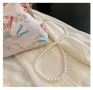 Detailed close-up of pearl shoulder strap and jacquard cherry blossom silk fabric