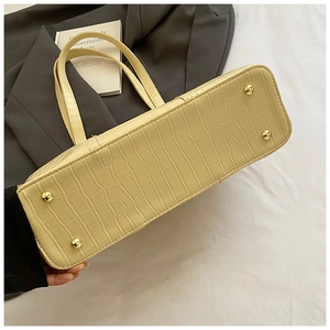 Gros plan du sac cabas jaune à motif crocodile avec pieds de protection en métal doré